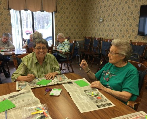 women smiling and painting door signs