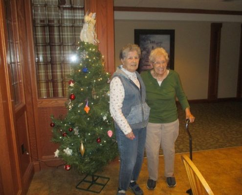 Two residents in front of Christmas tree