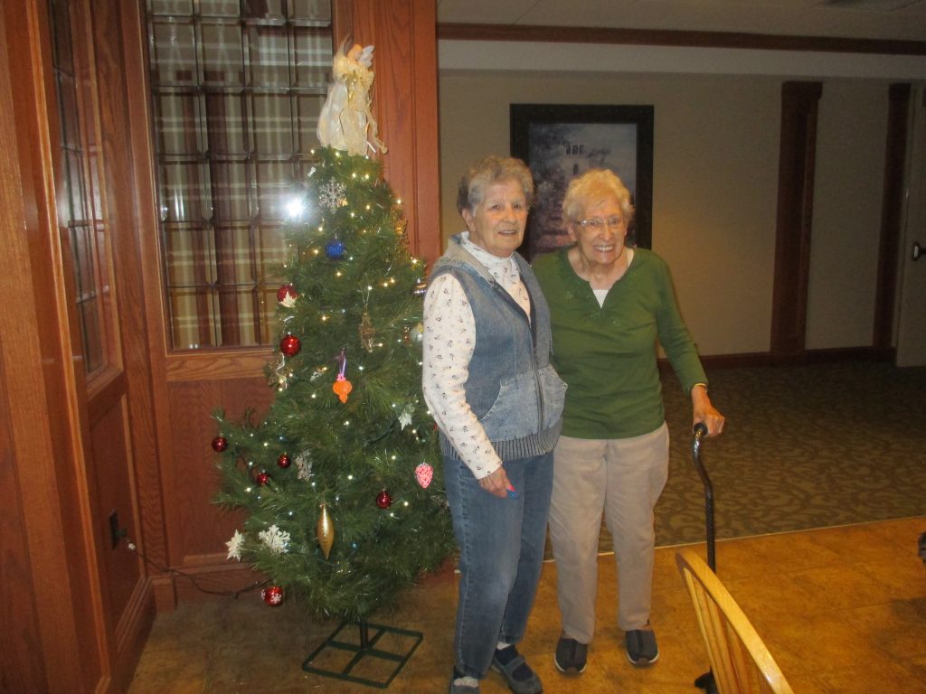Two residents in front of Christmas tree